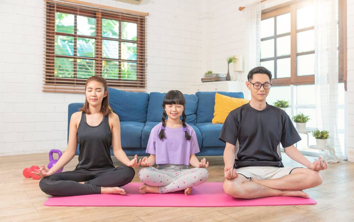 A family of three practicing yoga together in a bright living room.