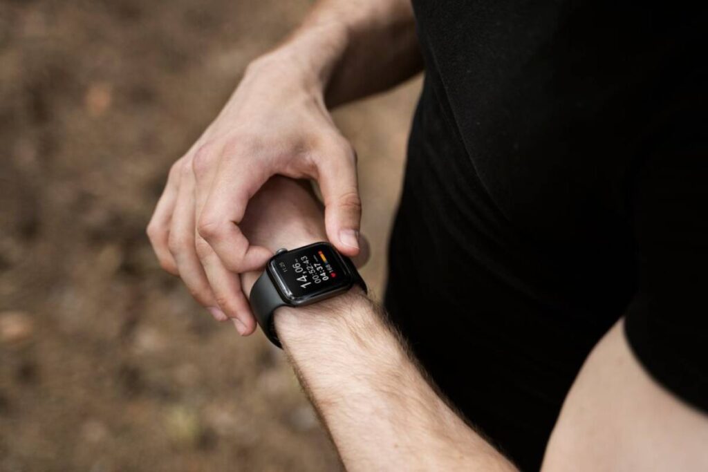 A person checking their smartwatch displaying heart rate and workout time during an exercise session.