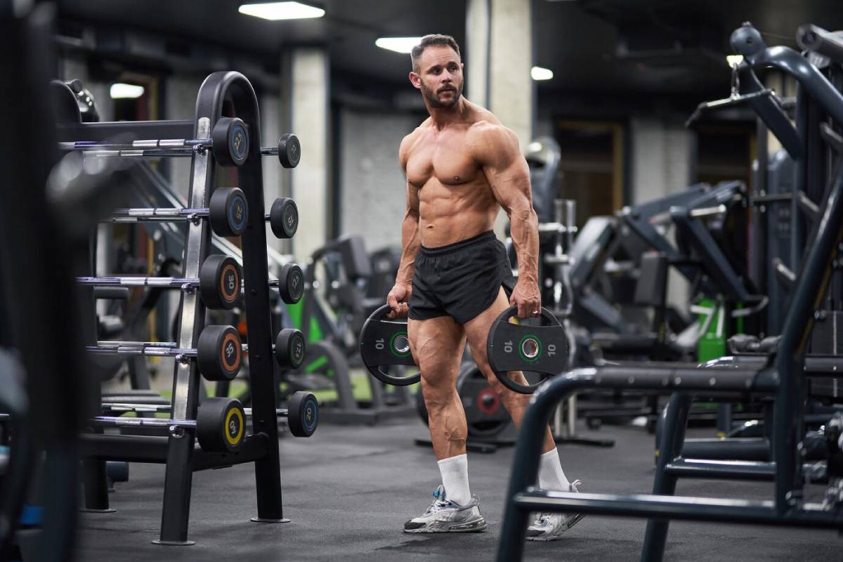 Muscular man lifting weights in a well-equipped gym.